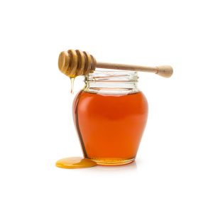 A glass of nature honey and honey dipper isolated on white background. Taken in Studio with a 5D mark III.